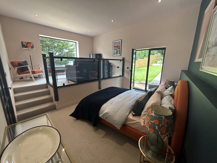 Bedroom in a new extension with a green feature wall and glazed doors to the garden